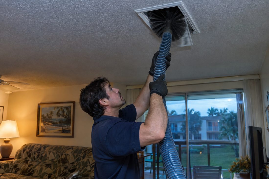 Duct cleaning hose and brush inserted into a supply vent at a 1970s low-rise condo building in Boynton Beach, FL